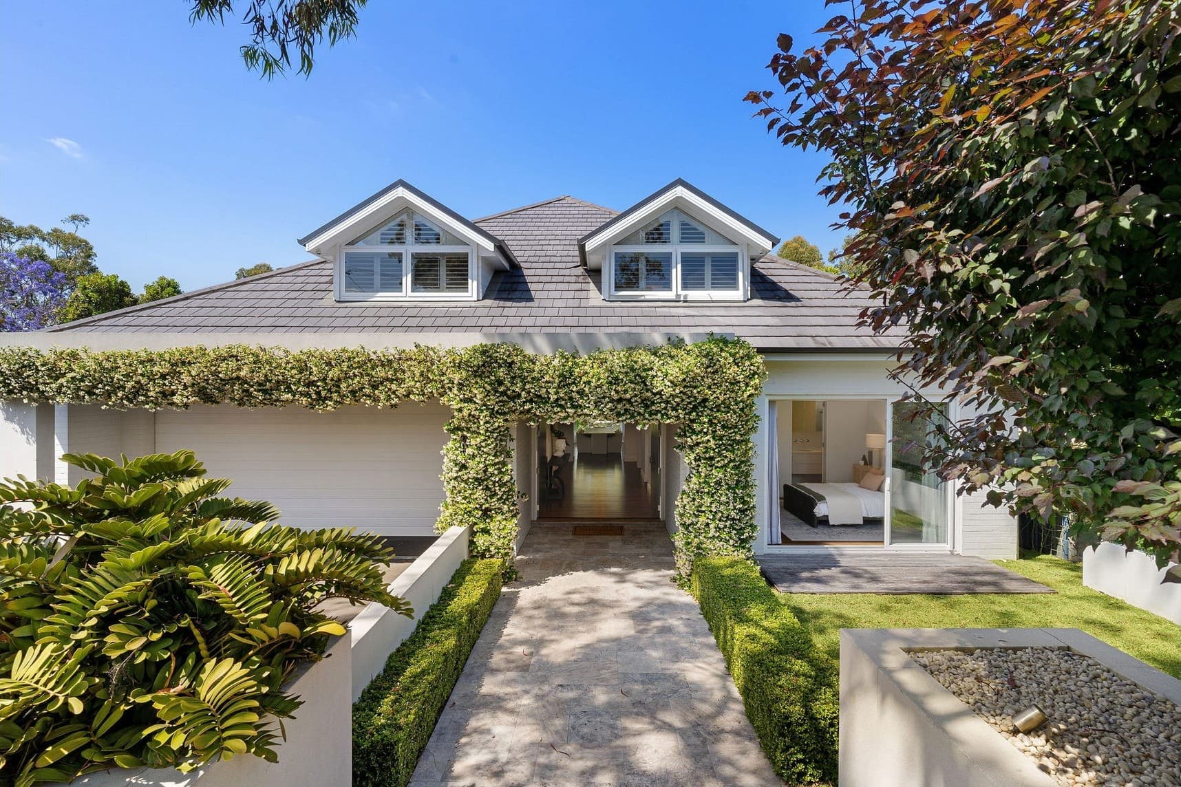 A hedge-framed approach to a renovated Sydney home.