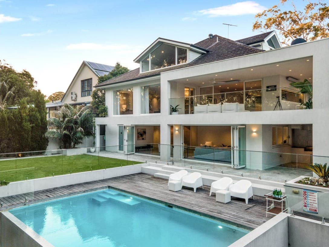 The rear elevation of the Blanche Street home at dusk, pool terrace below.